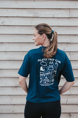 Fern wearing the navy Pilates Prep Club T-shirt, showing the illustrated back print