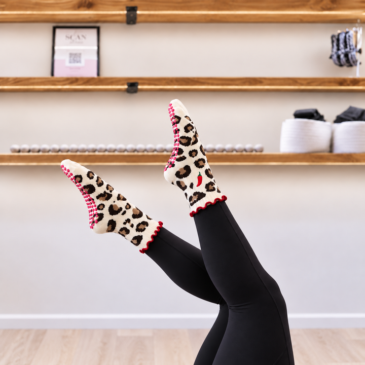 Hot Stuff leopard Pilates grip socks with red chilli embroidery and red frill, worn without a Pilates ball