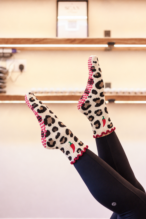 Hot Stuff leopard and chilli Pilates grip socks worn with black leggings in the Radiant studio