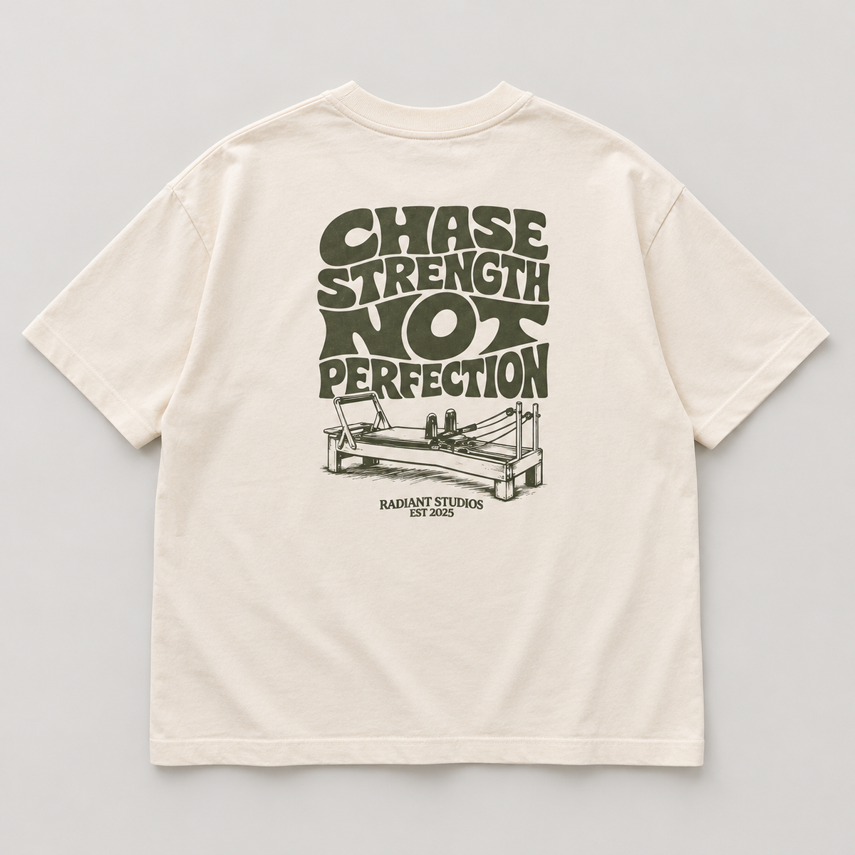 Back flat lay of cream oversized Radiant Pilates T-shirt with olive Chase Strength Not Perfection print and reformer illustration