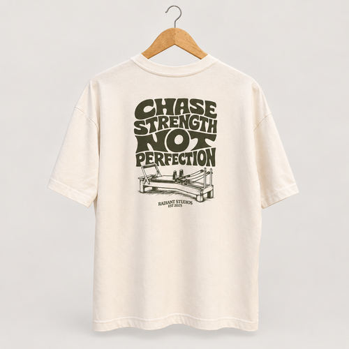 Cream Radiant Pilates T-shirt on wooden hanger, showing olive Chase Strength Not Perfection back graphic