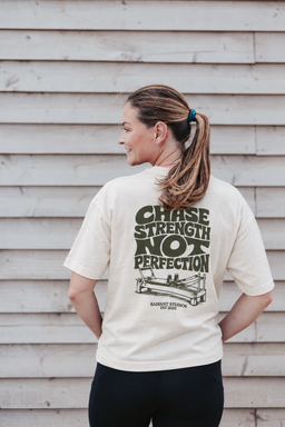 Fern wearing the cream Radiant Pilates T-shirt with olive Chase Strength Not Perfection back print