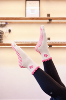 Studio Sweetheart 2.0 white and pink Pilates grip socks worn with black leggings in the Radiant studio